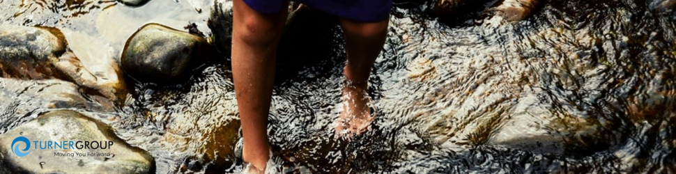 A person crossing a rocky river barefoot